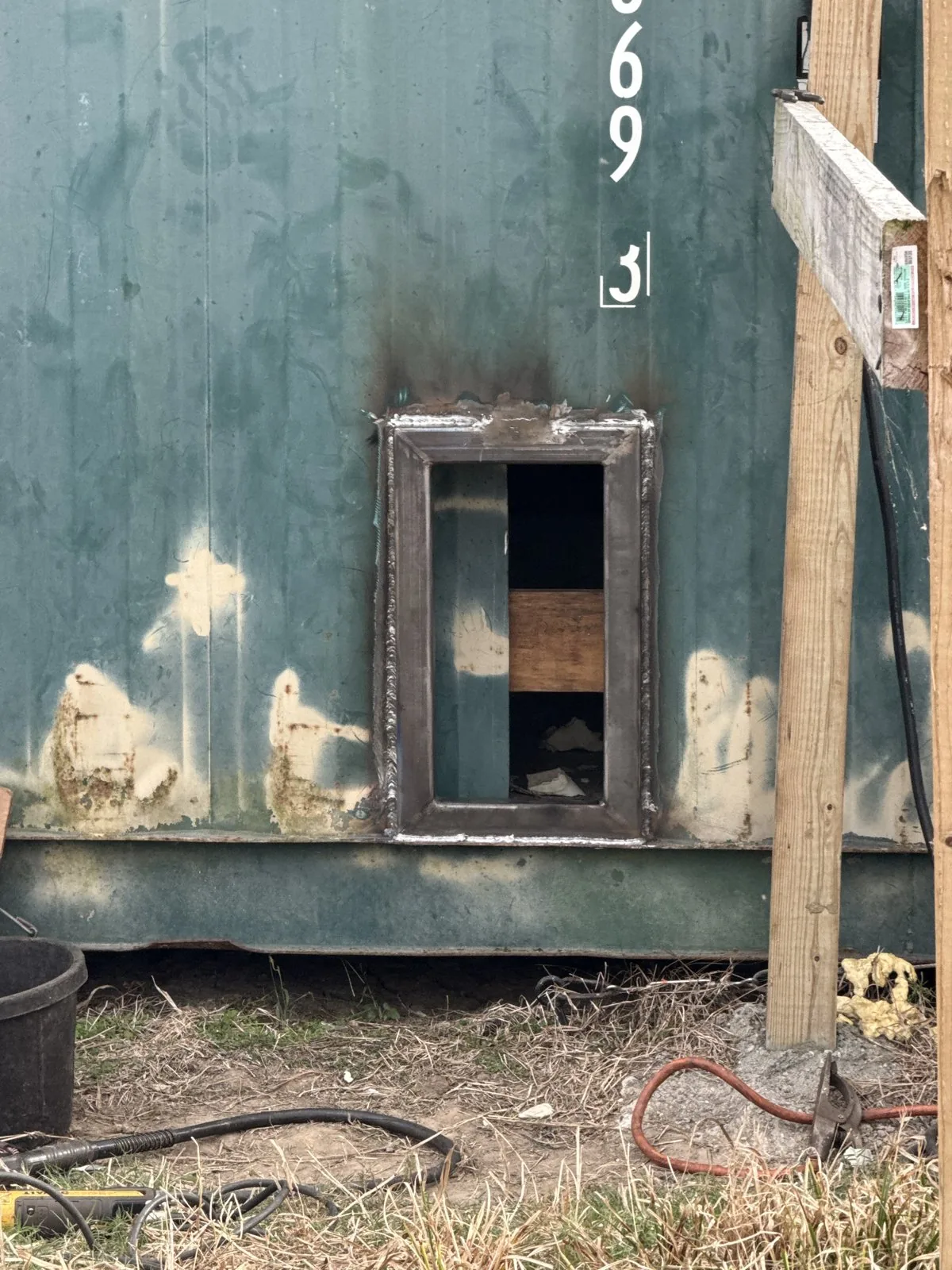 Framed window opening cut and welded into a shipping container wall